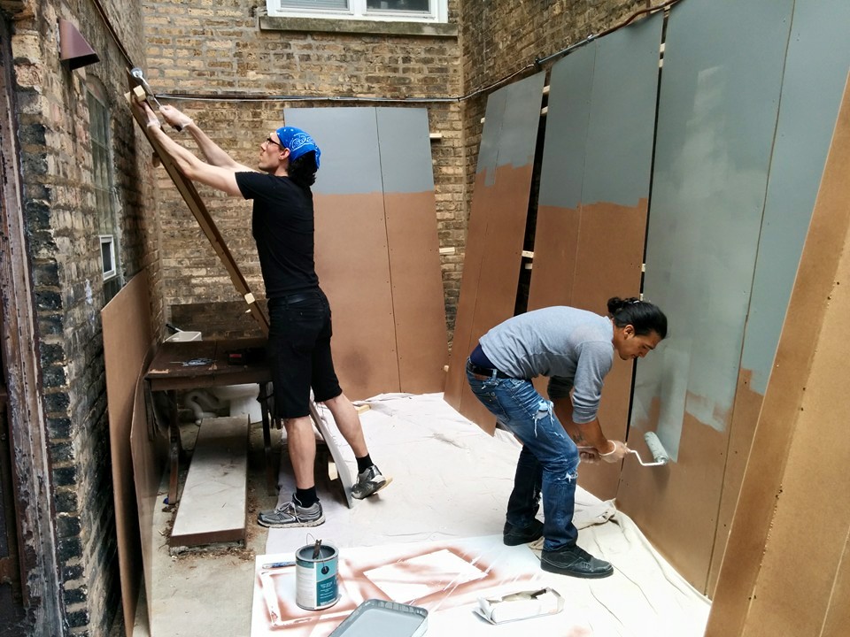 Volunteers paint sections of a full size model of a solitary confinement cell for an upcoming exhibit. (Photo: Kelly Hayes)